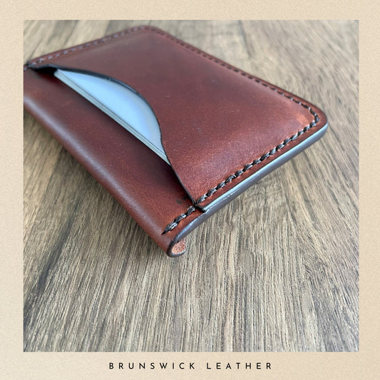 Brown leather wallet on a wooden surface with 'Brunswick Leather' branding.