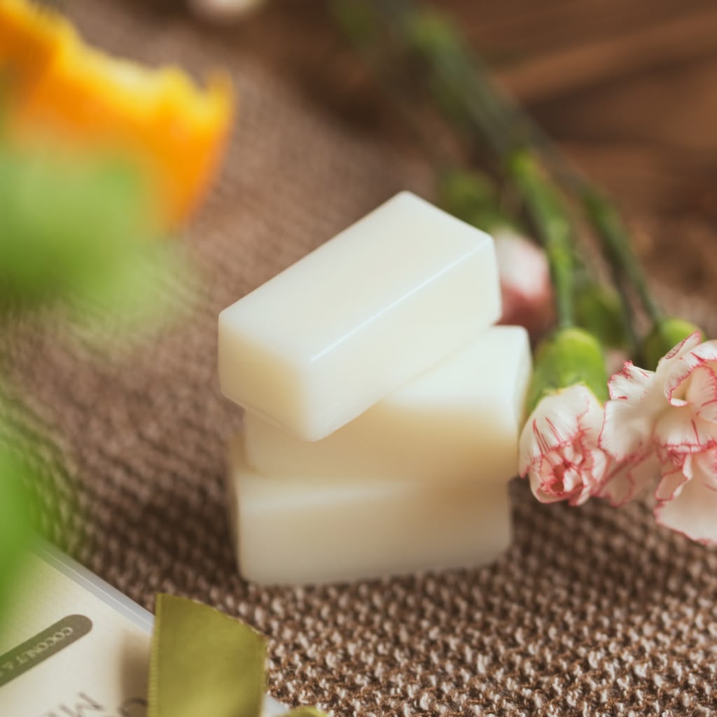 White wax melts on a textured surface with flowers in the background
