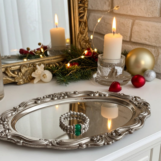 Agate green ring in a decorative setting with candles, mirror, and festive ornaments on a table.
