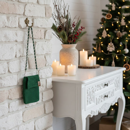 Green knitted bag hanging on a white brick wall with candles and a decorative plant.
