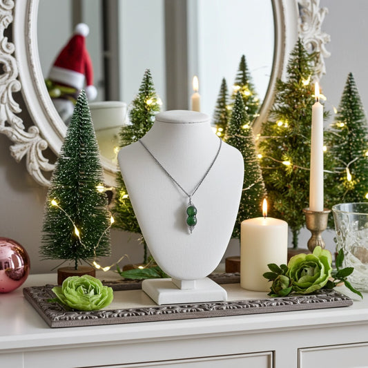 Jewellery display with pea pod necklace on a mannequin bust, surrounded by Christmas decorations including small trees and candles.