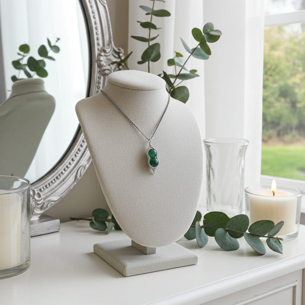 Necklace on a necklace stand with candles and eucalyptus leaves in the background