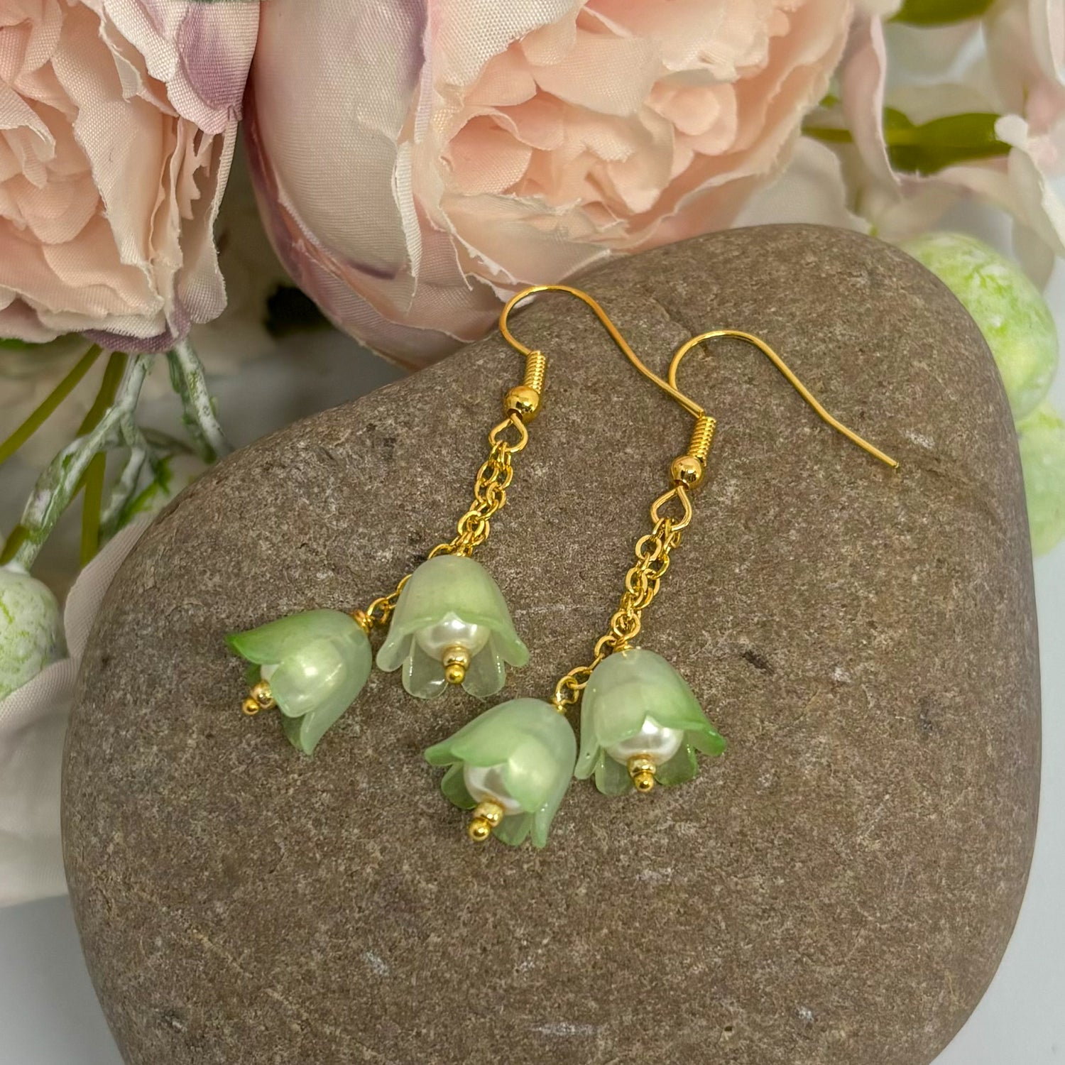 green tulip earrings with gold hooks on a stone