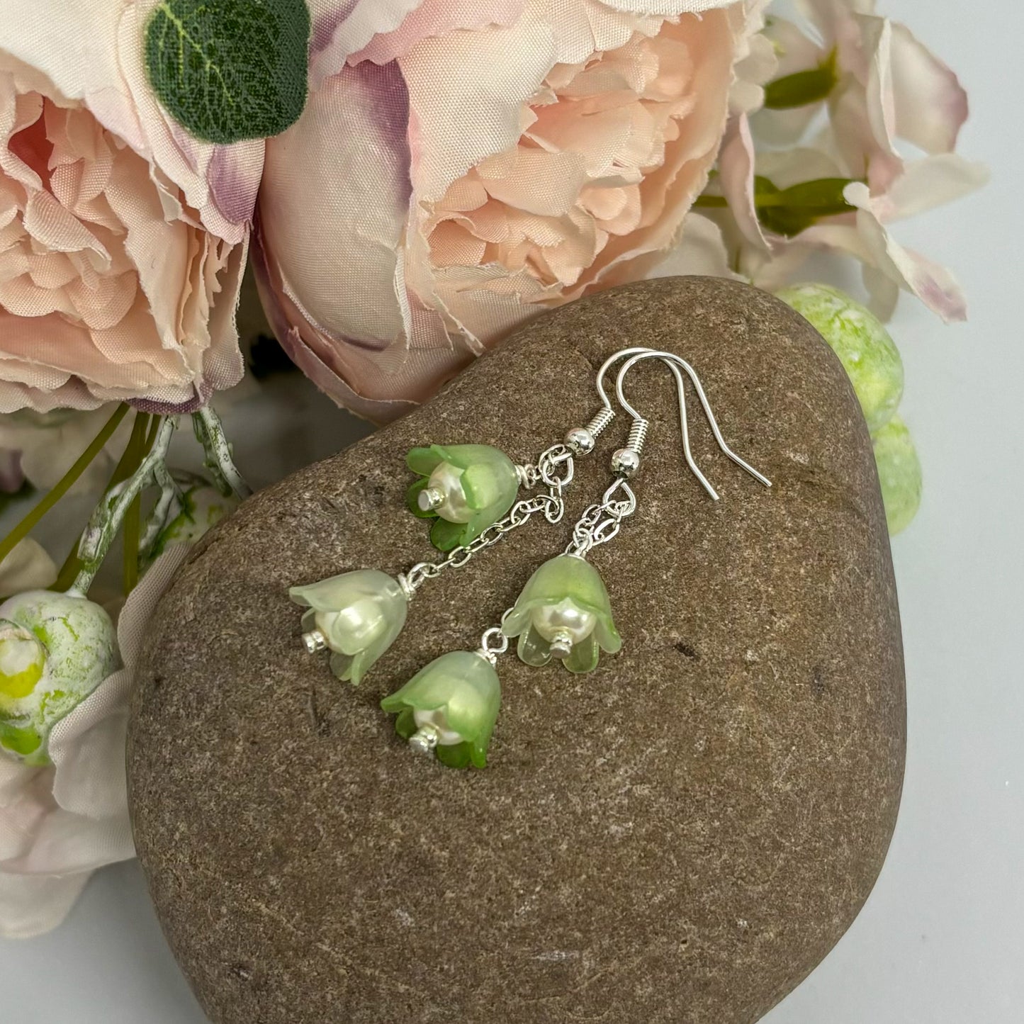 green tulip earrings with silver hooks on a stone