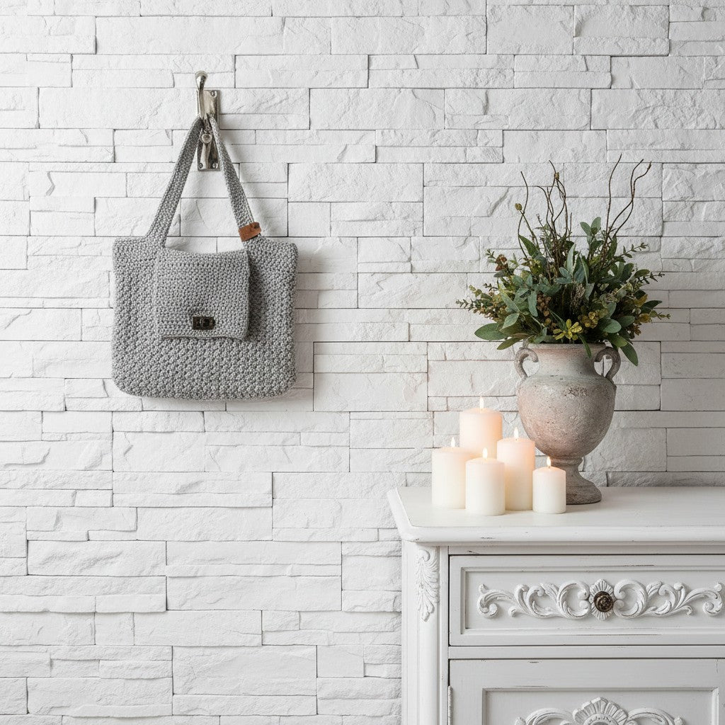 Grey textured bag hanging on a white brick wall with a decorative cabinet and candles in the foreground.