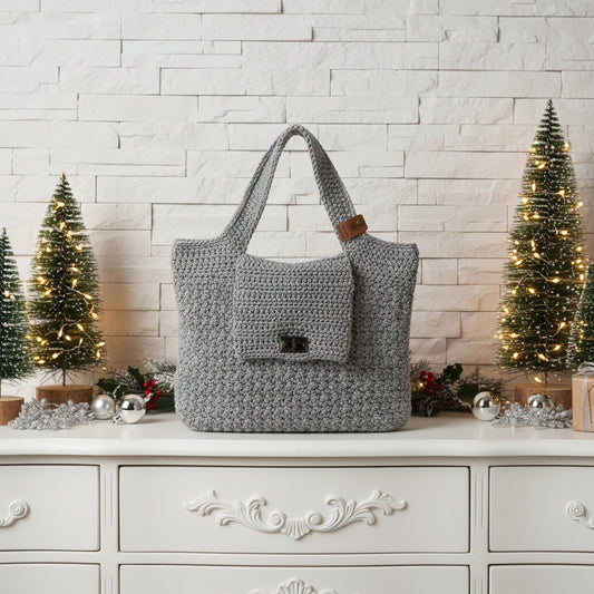 Grey crochet bag on a white surface with Christmas decorations in the background