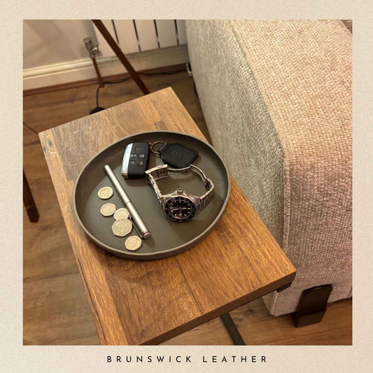 Tray with keys, watch, and coins on a wooden table with 'Brunswick Leather' branding.