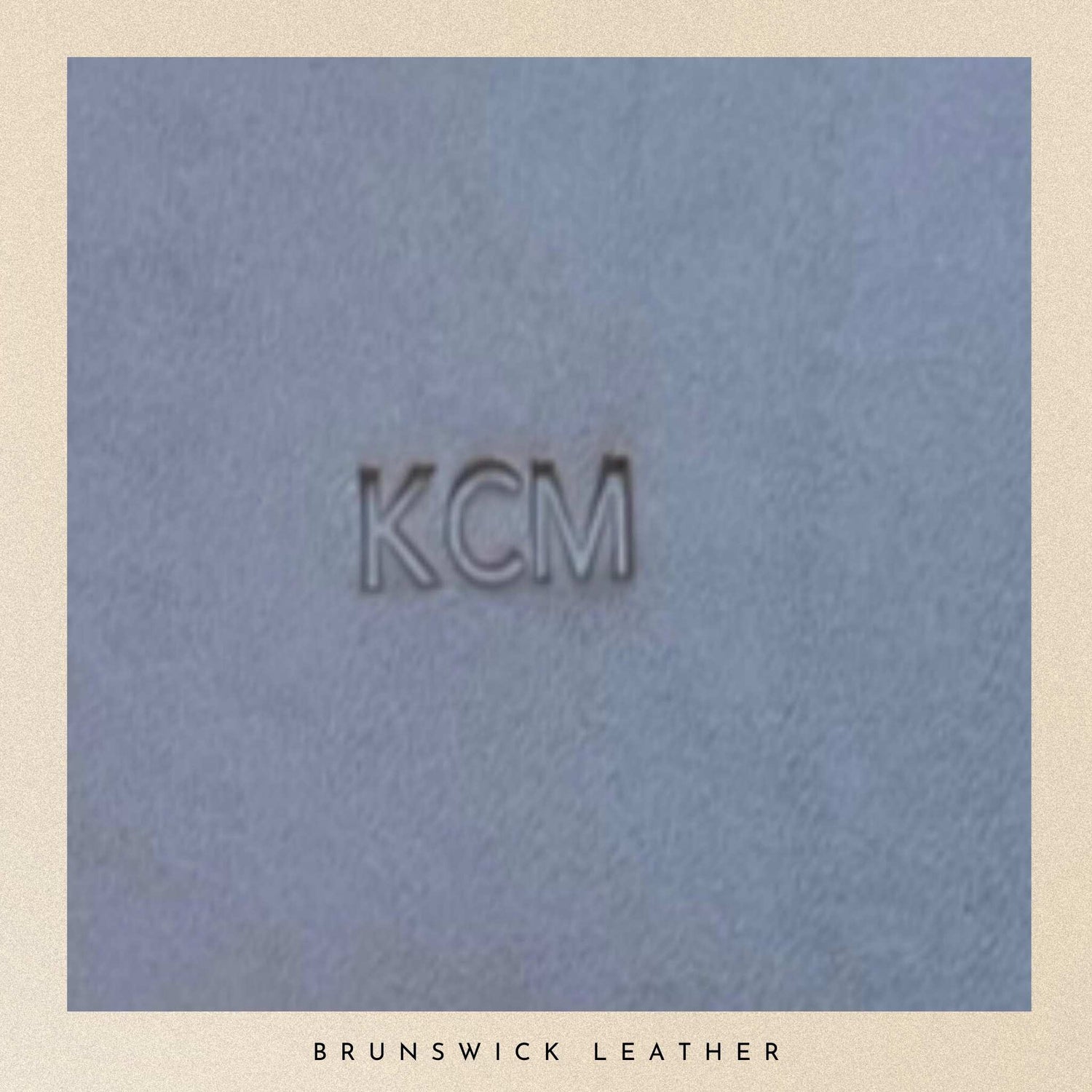 Text 'KCM' on a textured grey leather background with 'Brunswick Leather' at the bottom.