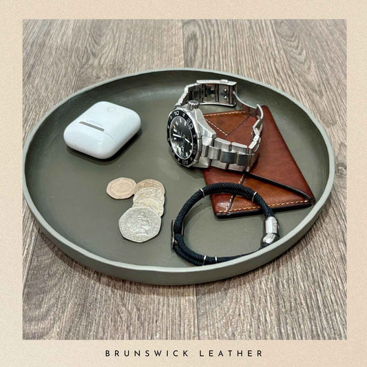 Tray with a watch, wallet, and coins on a wooden surface with 'Brunswick Leather' branding.