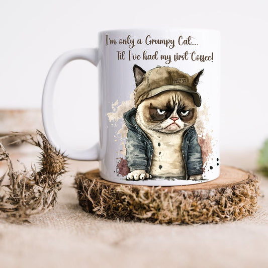 Grumpy cat in a denim jacket and canvas hat. Quote at the top of the white ceramic mug. The mug is placed on a rustic wooden plinth.