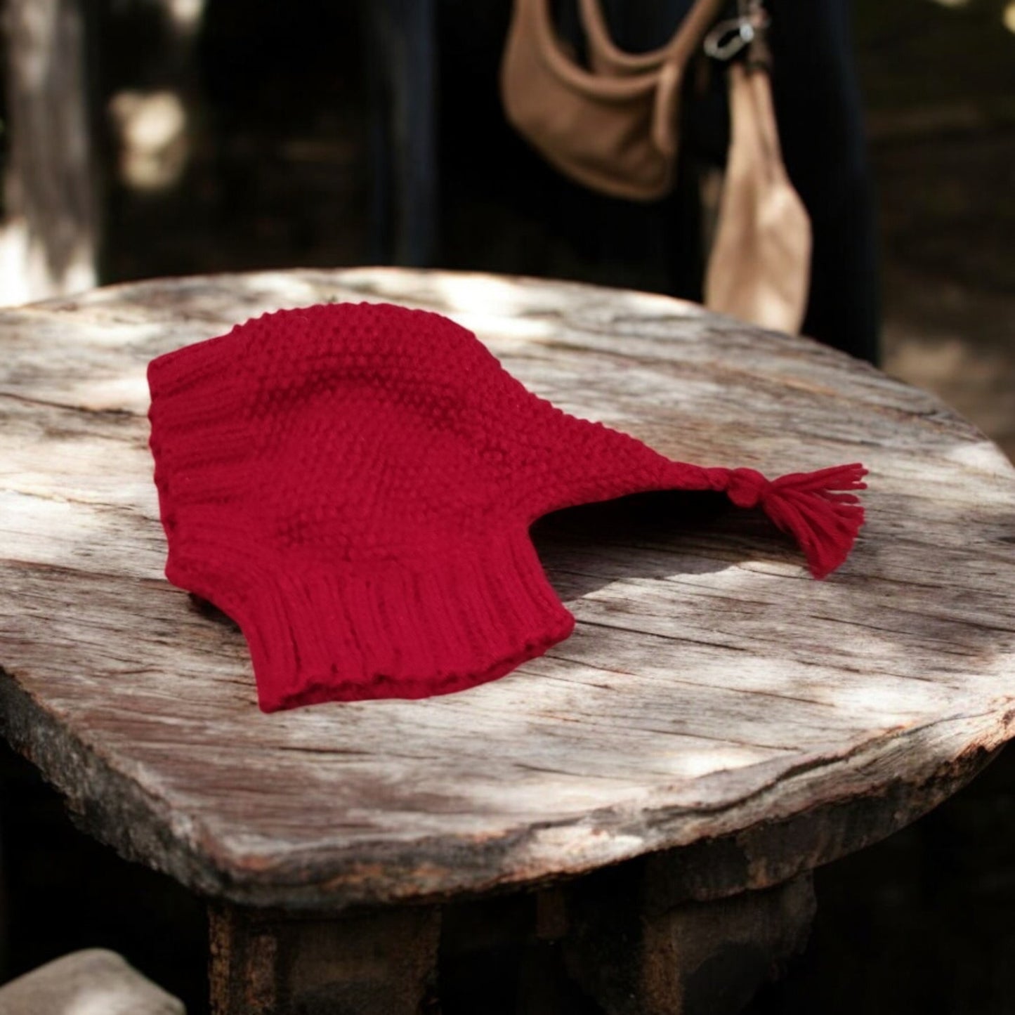 A handmade dog hat with tassel on a rustic piece of wood