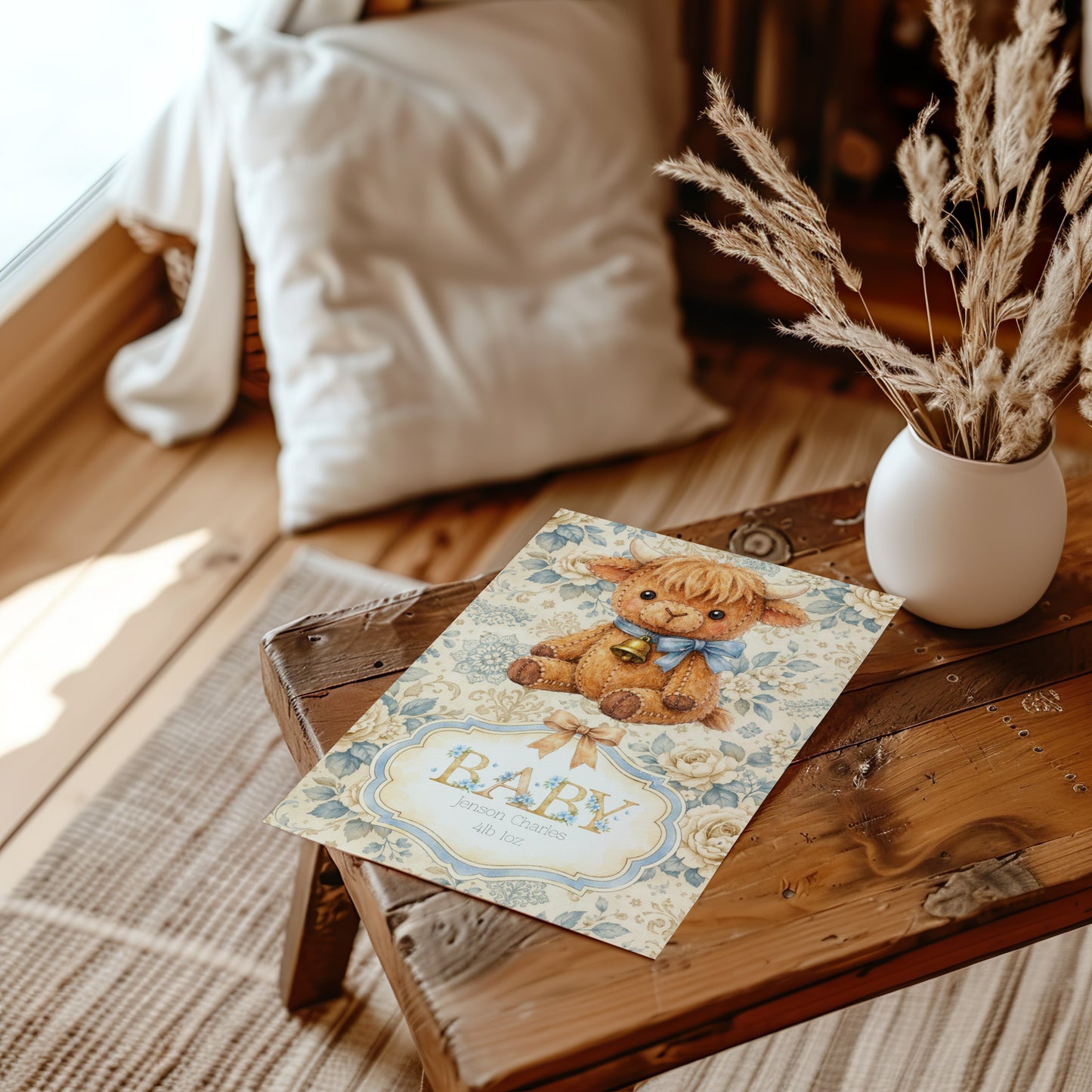 Baby shower card with highland cow design on a wooden table with decorative elements.