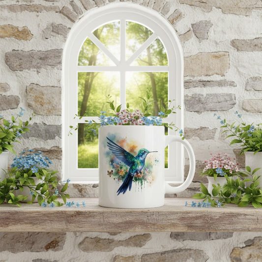 White mug with a colourful hummingbird design on a windowsill with plants and a stone wall background