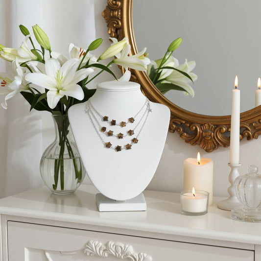 Jewellery display with labradorite necklace on a bust, flowers in a vase, and candles on a decorative table.