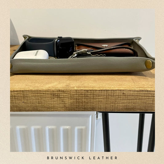 Tray with assorted items on a wooden surface, featuring 'Brunswick Leather' branding.