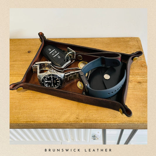 Wooden tray with a watch, keys, and phone on a wooden surface, branded 'Brunswick Leather'.