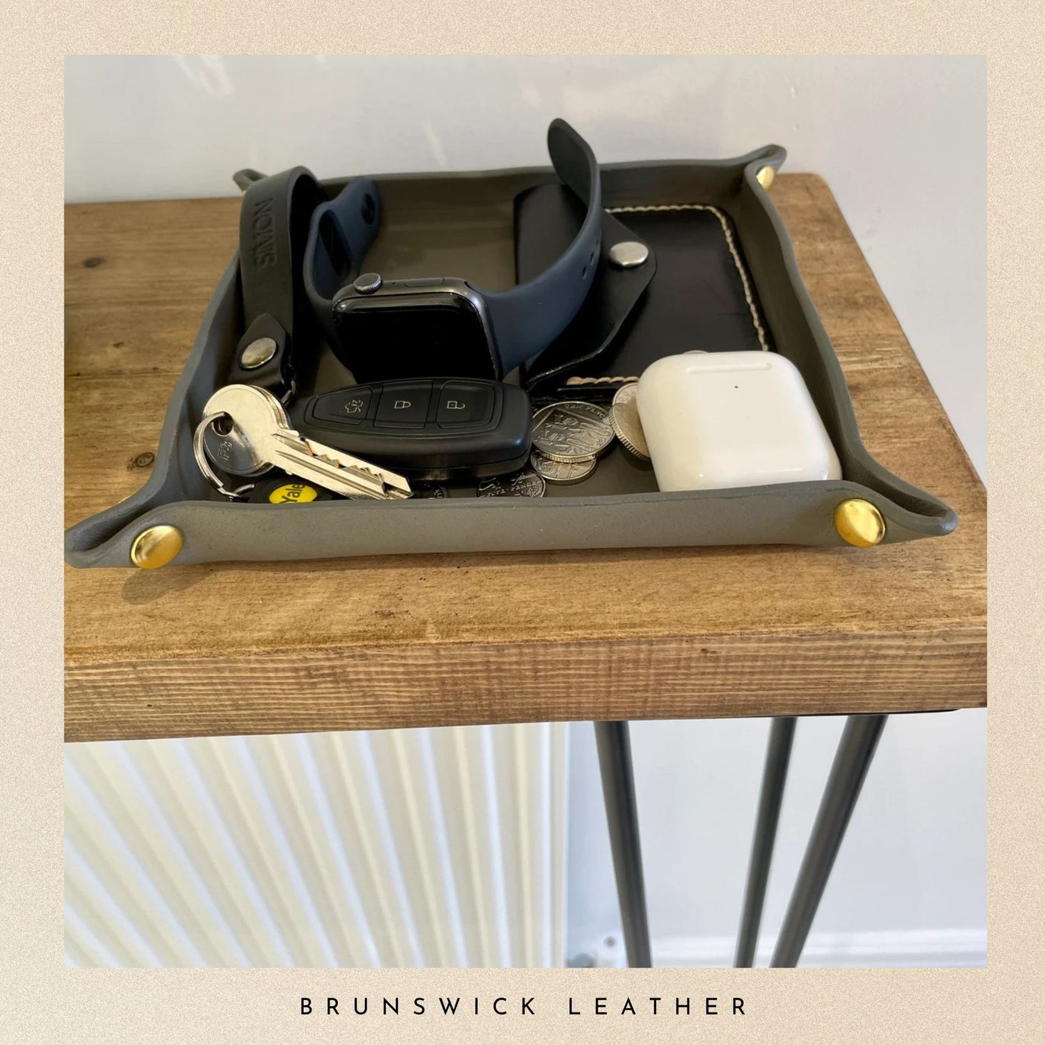 Tray with various items on a wooden surface, featuring the brand 'Brunswick Leather'.