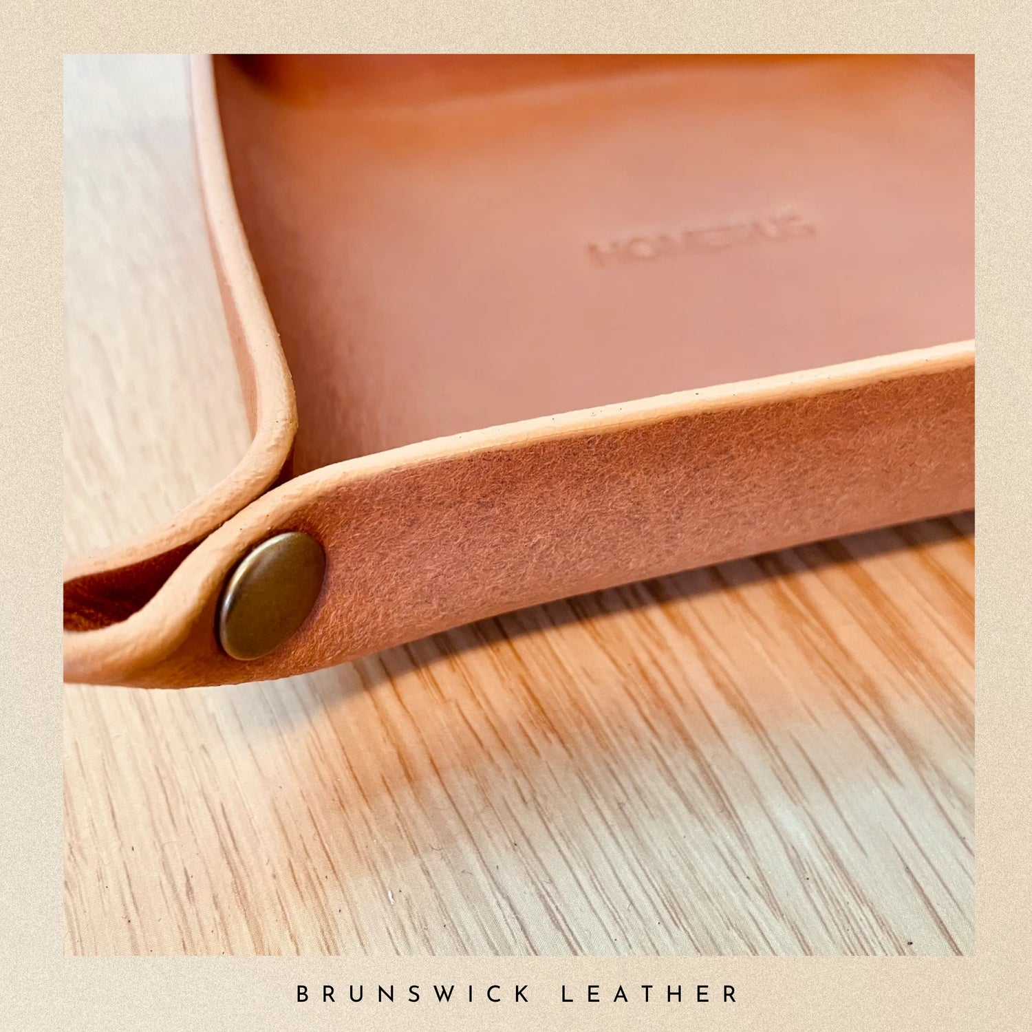 Close-up of a leather tray with branding on a wooden surface, featuring the brand 'Brunswick Leather'.