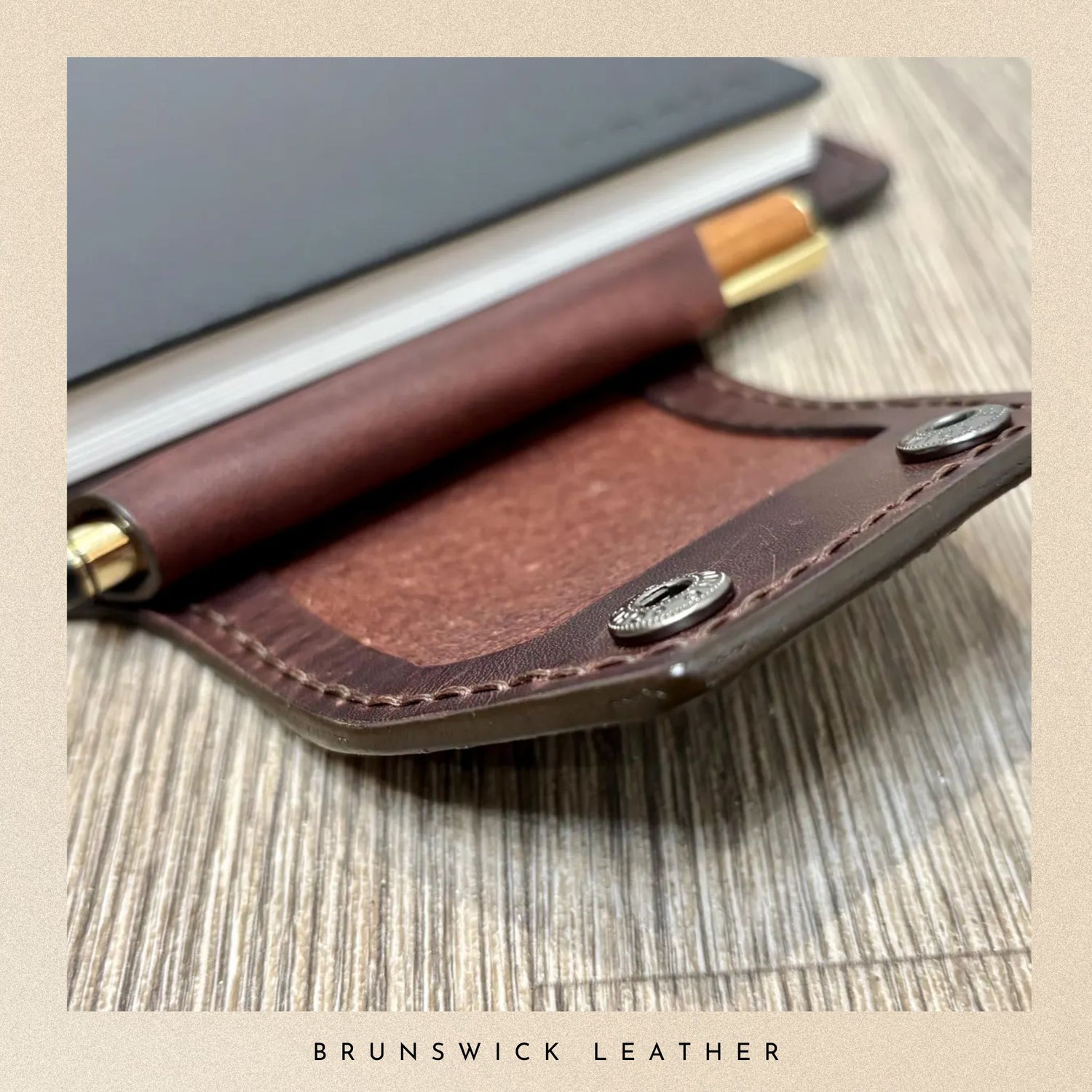Brown leather wallet with gold accents on a wooden surface, branded 'Brunswick Leather'.