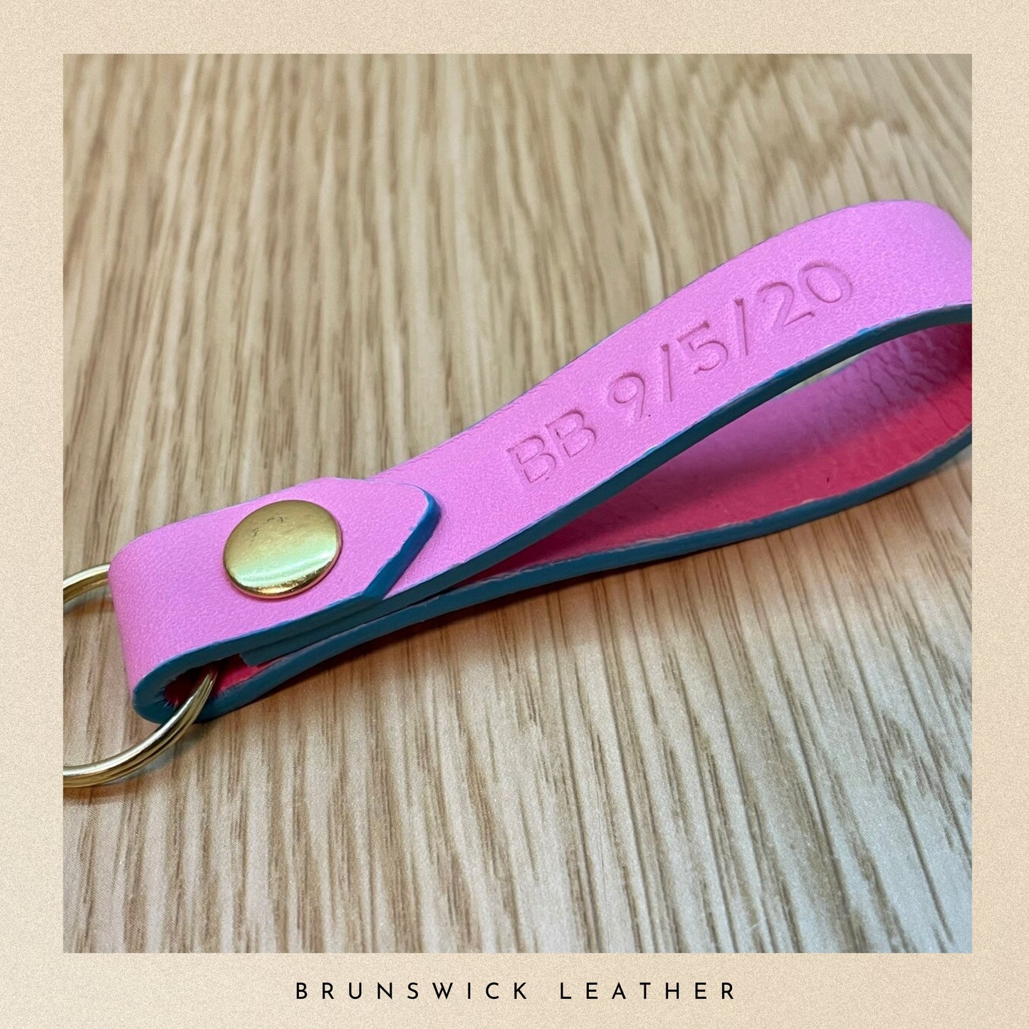 Pink leather keychain with gold accent on a wooden surface, branded 'Brunswick Leather'.