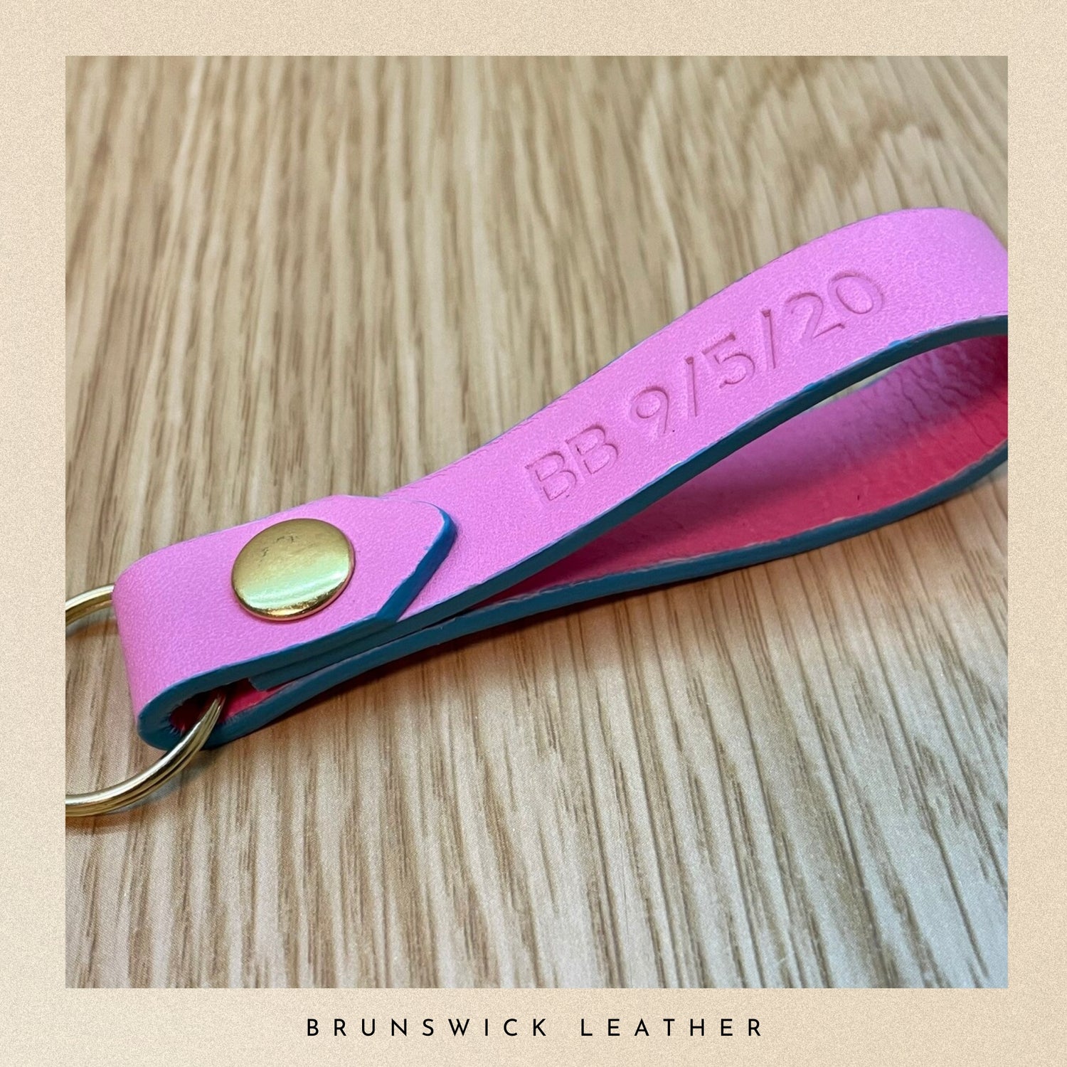 Pink leather keychain with gold accent on a wooden surface, branded 'Brunswick Leather'.