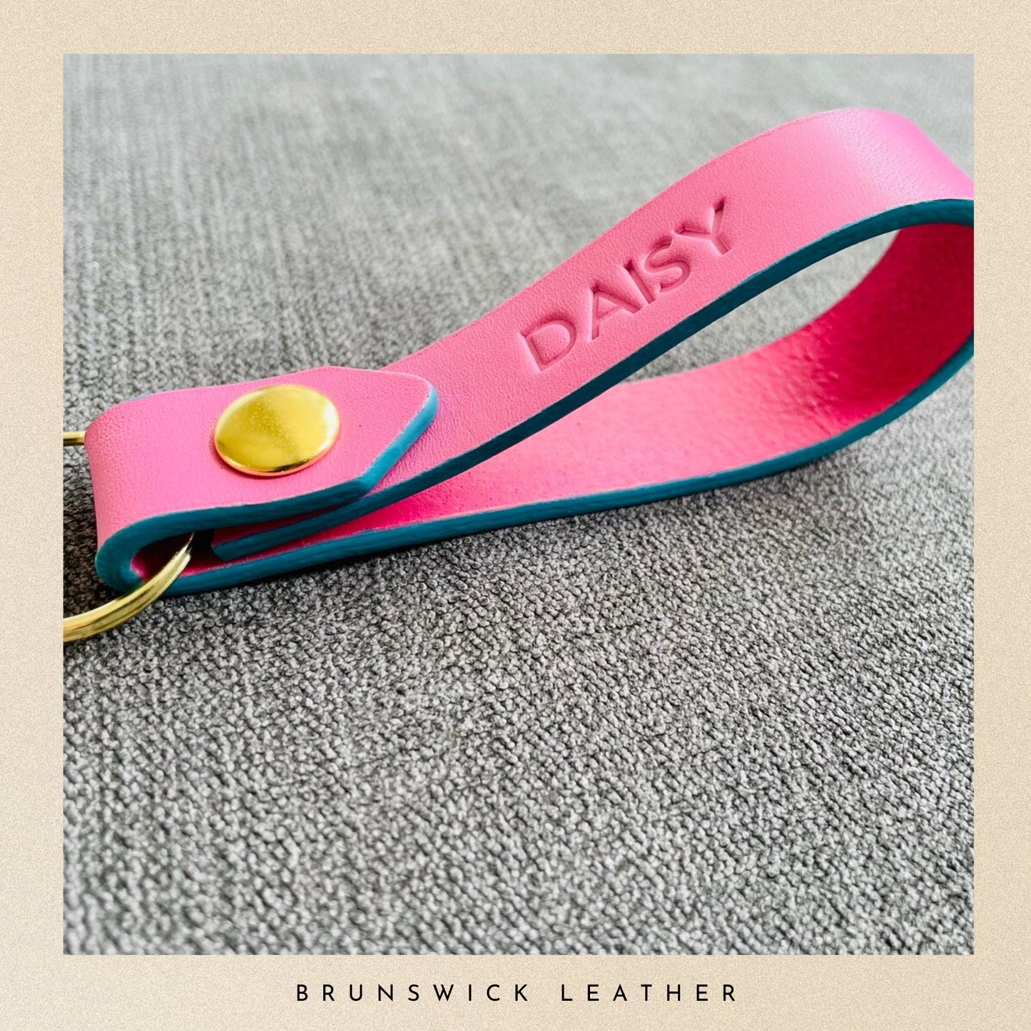 Pink leather keychain with 'DAISY' engraving on a textured surface, branded 'Brunswick Leather'.