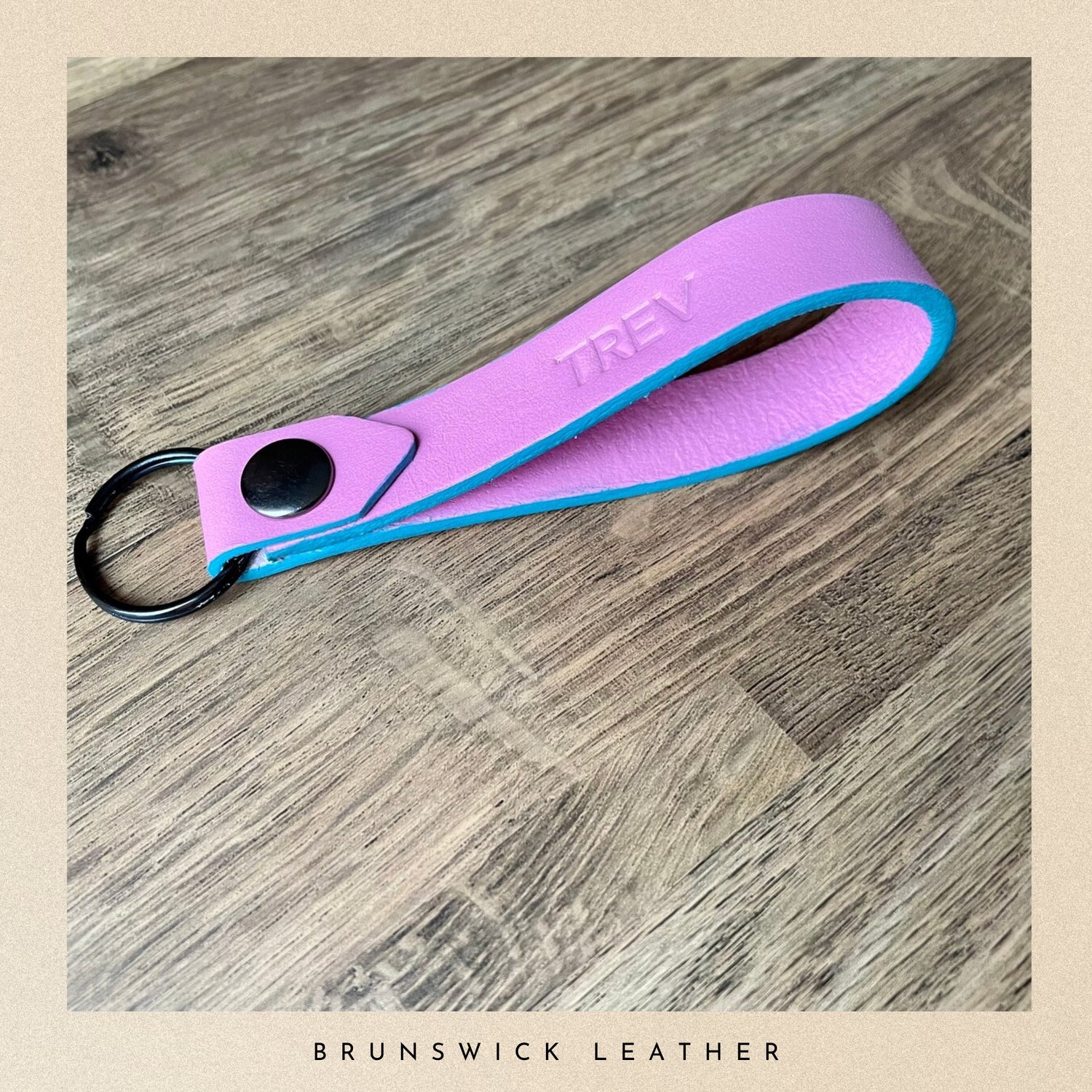 Pink and blue keychain with 'Trey' branding on a wooden surface, labeled 'Brunswick Leather'.