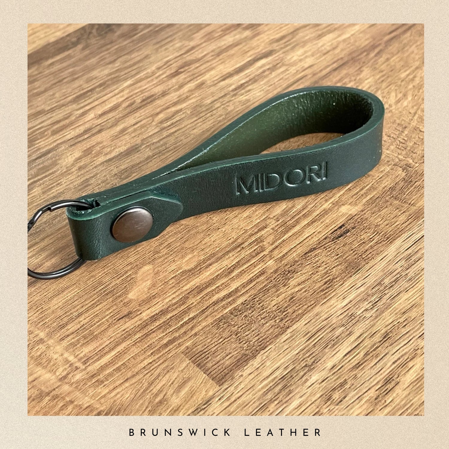 Green leather keychain with 'MIDORI' branding on a wooden surface