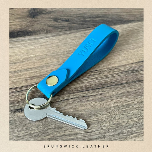 Blue keychain with a key on a wooden surface, branded 'Yuchy'.