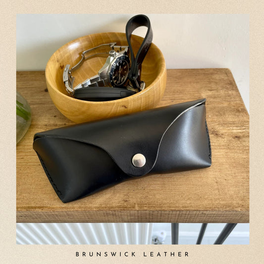 Black leather case on a wooden surface with 'Brunswick Leather' branding.