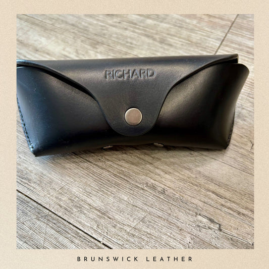 Black leather case with 'Richard' branding on a wooden surface, featuring 'Brunswick Leather' text.