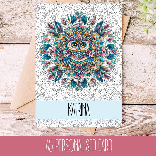 A personalised birthday card with a mandala owl design, featuring the name Katrina, laid on a wooden background with a white envelope.