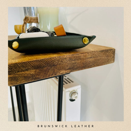 Black bowl with gold accents on a wooden surface, featuring 'Brunswick Leather' branding.