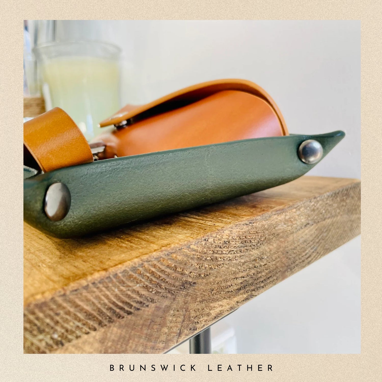 Green leather tray with brown accents on a wooden surface, featuring 'Brunswick Leather' branding.