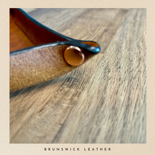 Close-up of a leather product on a wooden surface with 'Brunswick Leather' branding.