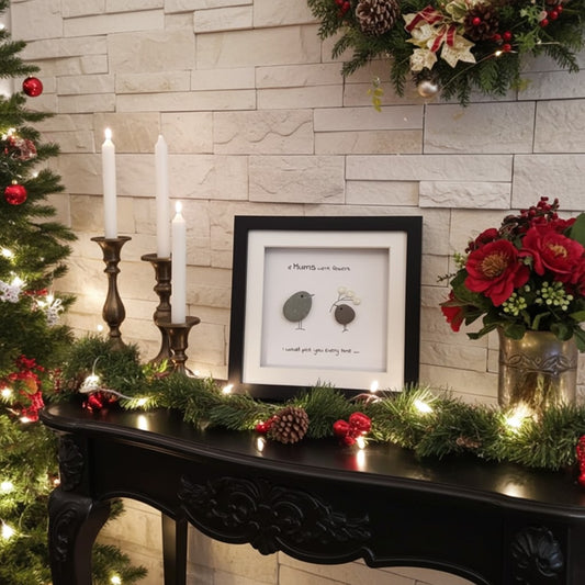 Decorated Christmas living room with a tree, candles, and framed pebble picture on a mantelpiece.