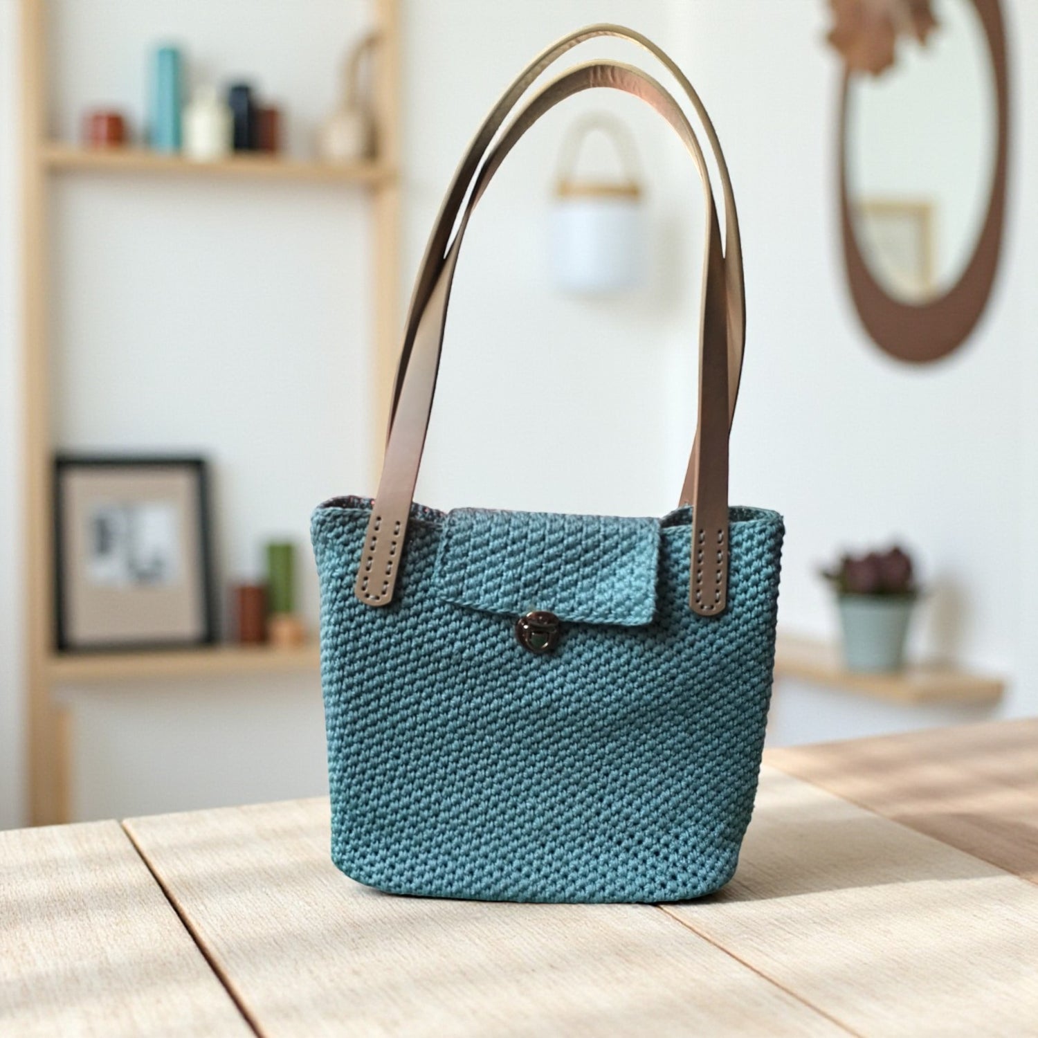 crochet shoulder bag standing on a table with a modern lounge in the background