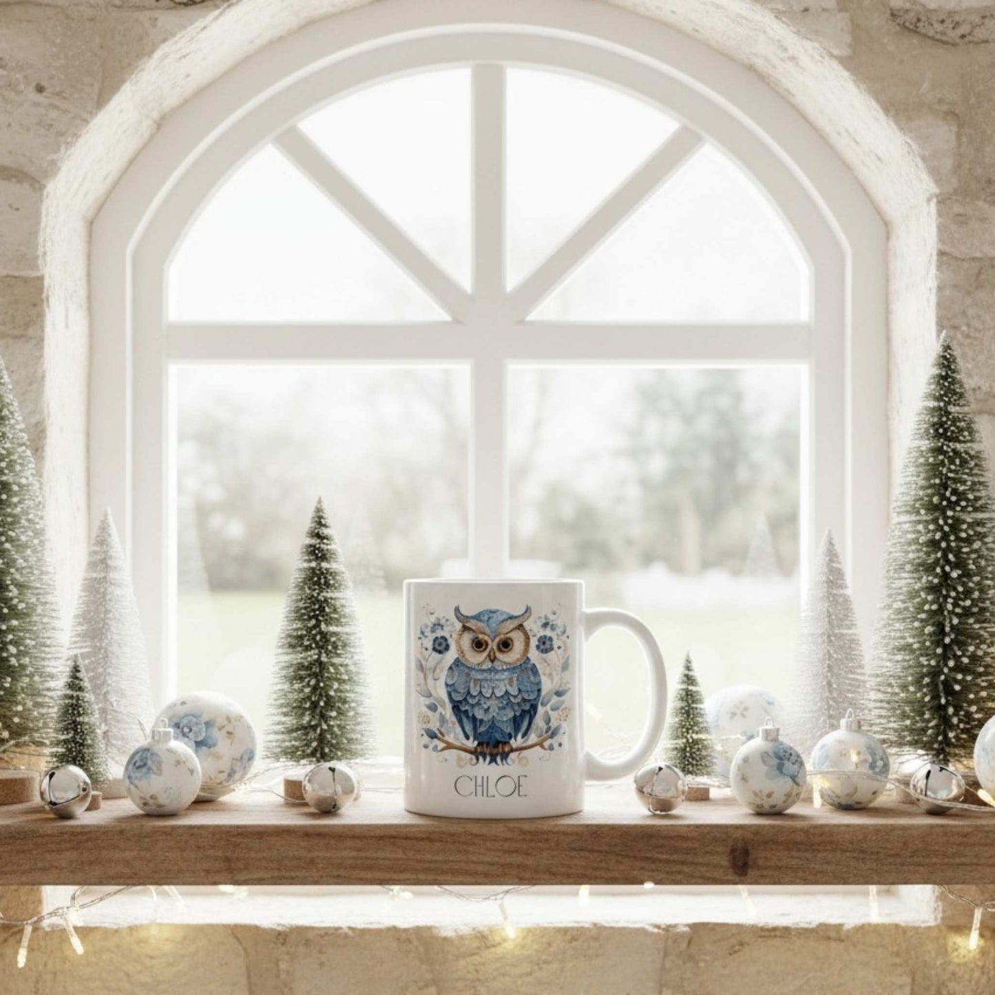 White mug with owl design on a windowsill with decorative Christmas items