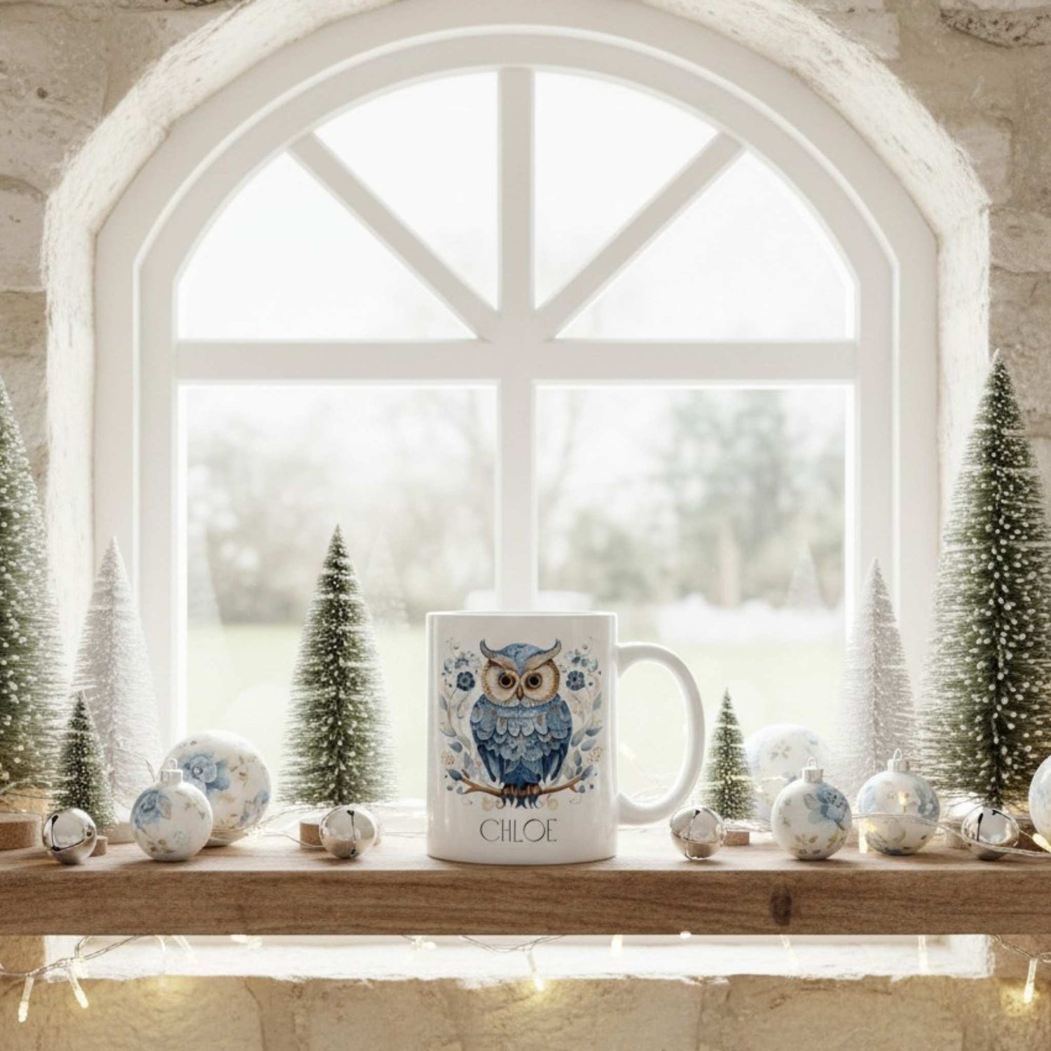 White mug with owl design on a windowsill with decorative Christmas items