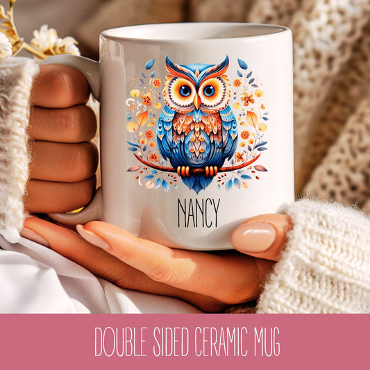 A double-sided ceramic coffee mug with a colourful owl design and the name 'Nancy' printed on it.