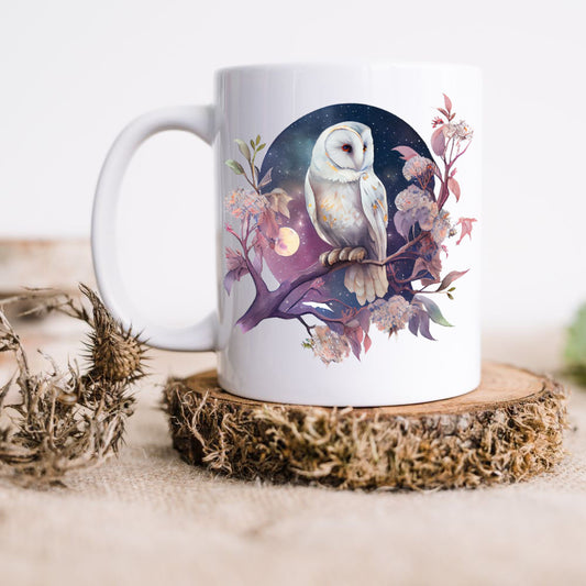 A white ceramic mug with a printed image of an owl, flowers, and leaves on a wooden surface.