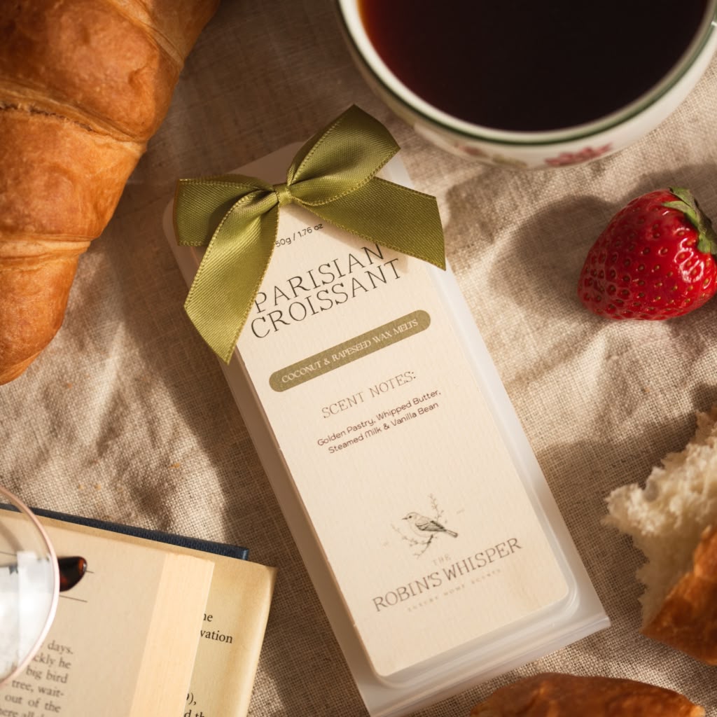Book with a Parisian Croissant wax melt croissant, and strawberry on a textured surface.