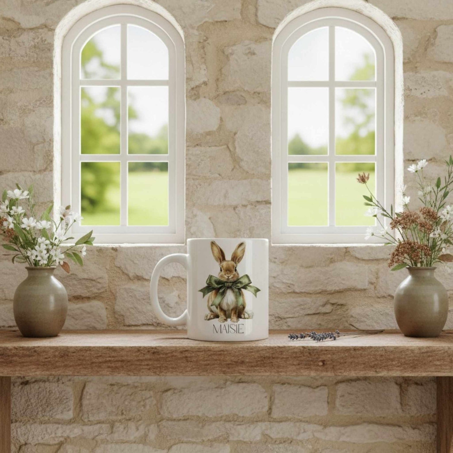 Mug with a hare design on a wooden table in front of stone walls and windows.