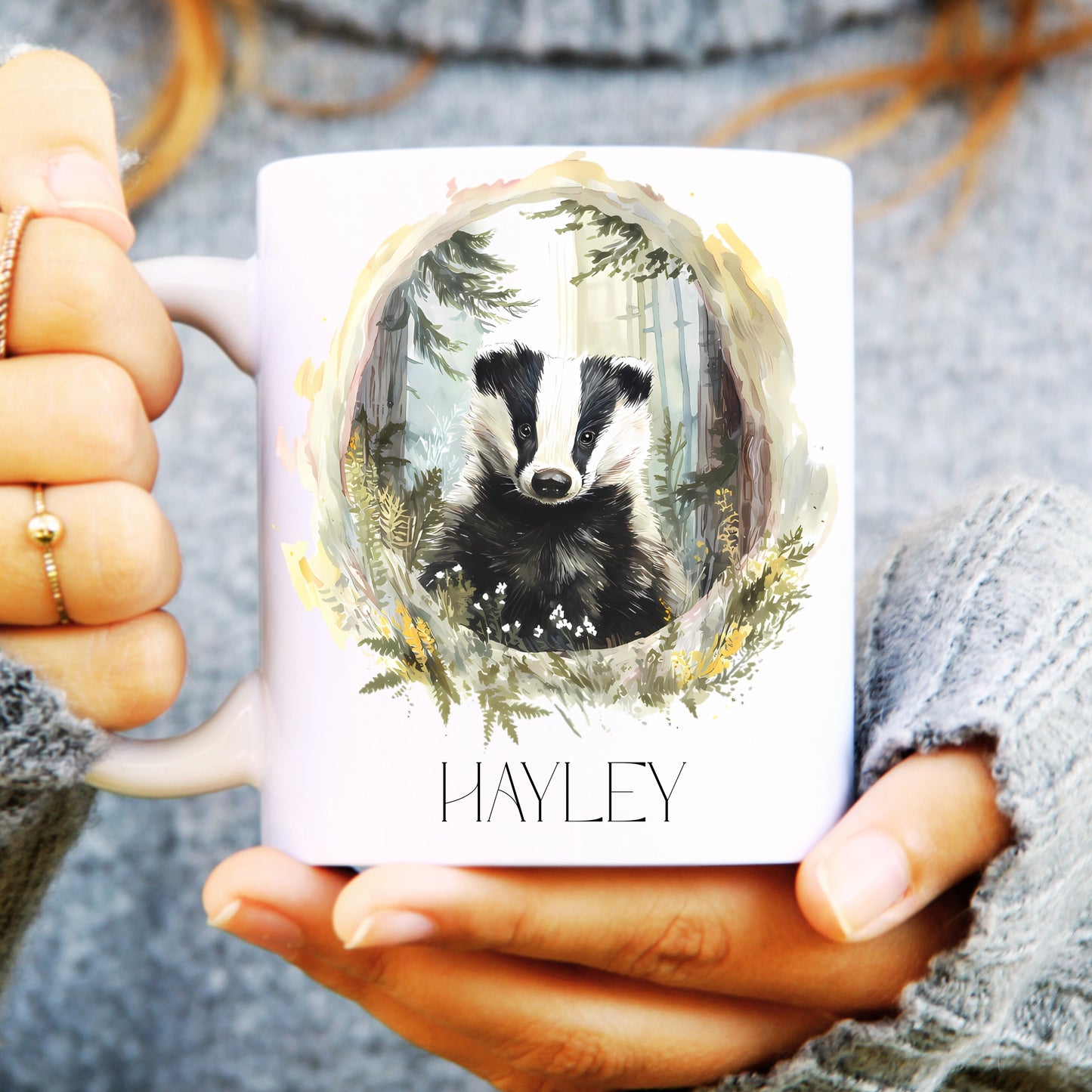 Person holding a mug with a badger design and 'Hayley' text.