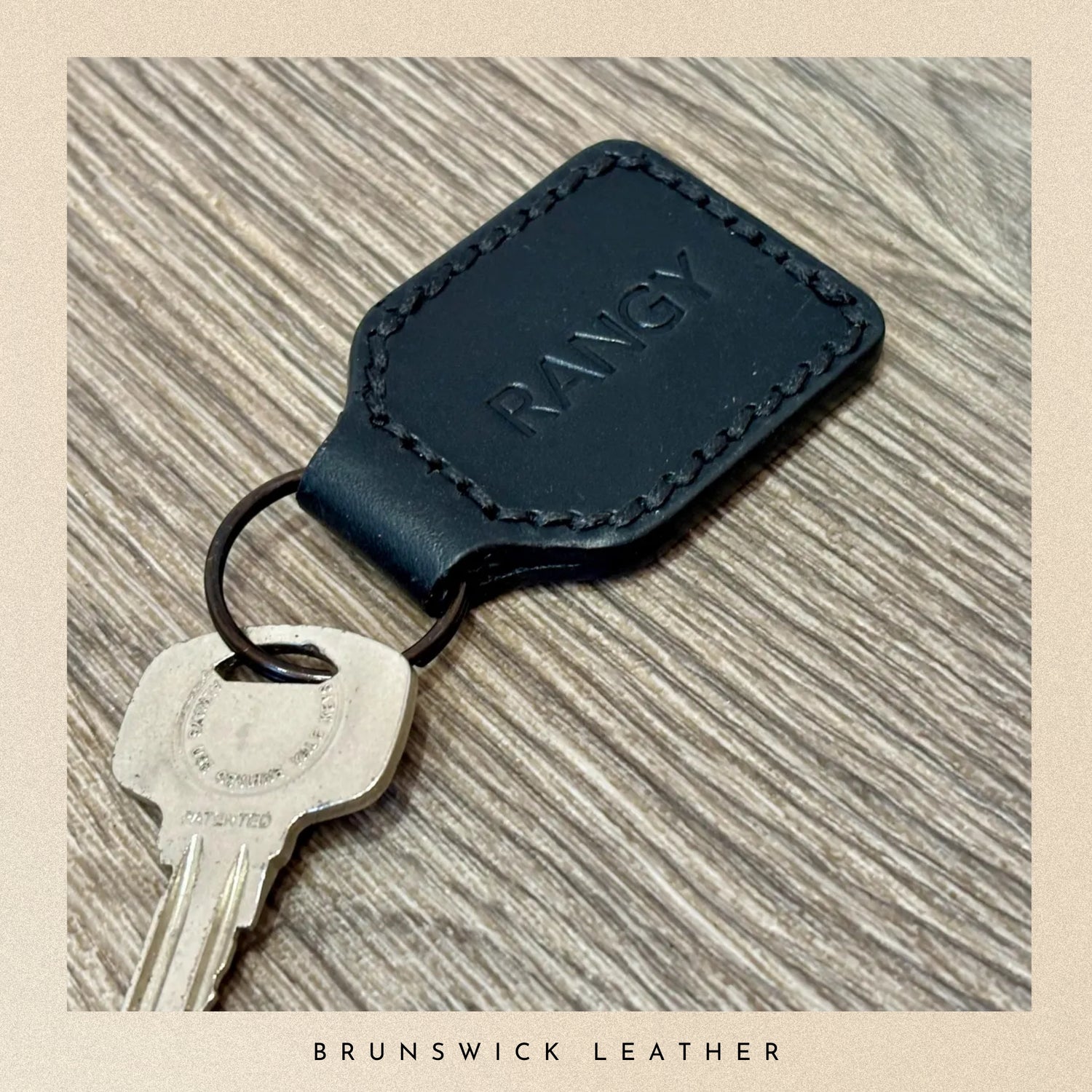 Blue leather key fob with 'RANGY' branding on a wooden surface, featuring the brand 'Brunswick Leather'.