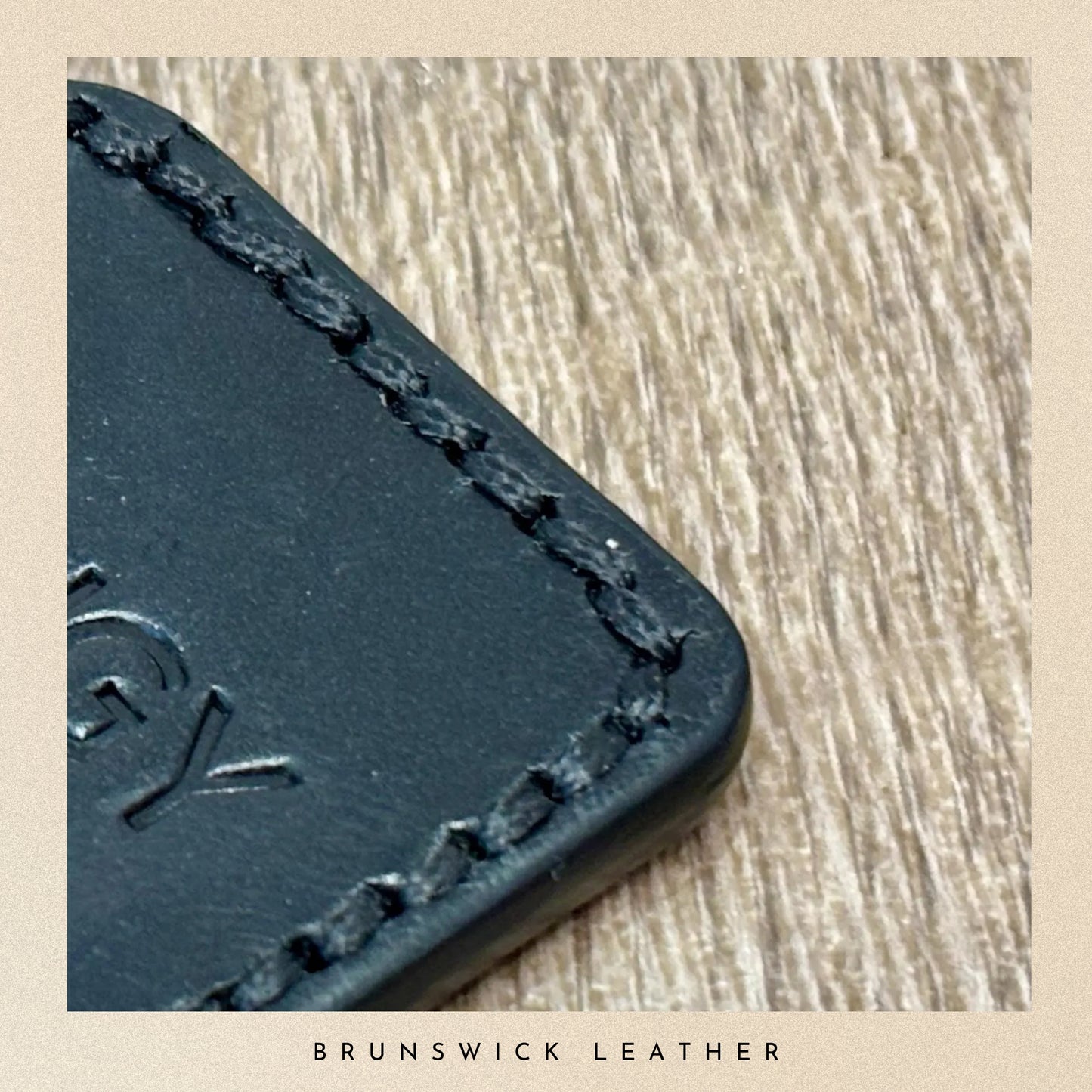 Black leather product with stitching detail on a wooden surface, branded 'Brunswick Leather'.