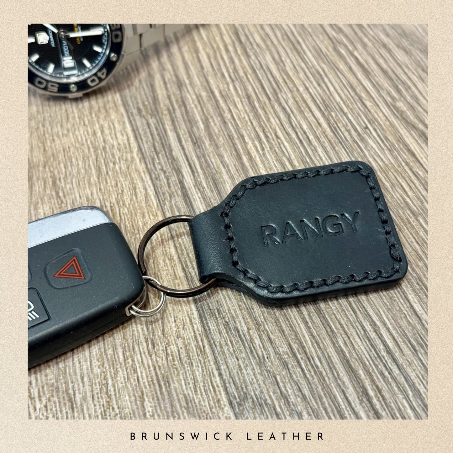 A personalised black key fob holding a car key on a wooden surface