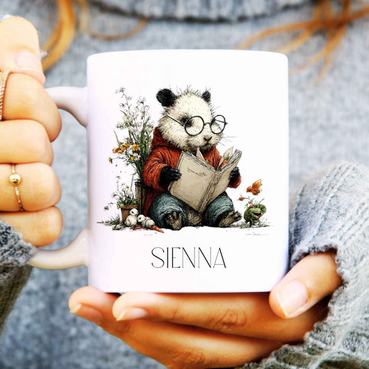 Person holding a mug with a panda reading a book illustration and 'SIENNA' branding.
