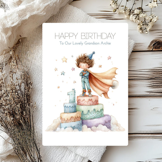 Personalised grandson card with a number 1 and little boy in a cape on top of cake.