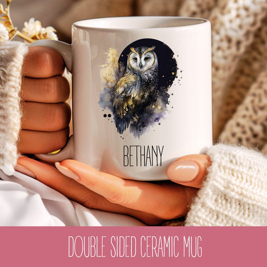 A personalised ceramic coffee mug with a celestial owl design and the name 'Bethany' printed on the side, held in a person's hand.